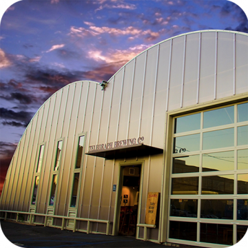 The outside walls of a brewery are covered with Skypoly Hercules panels and a glass and metal garage door.