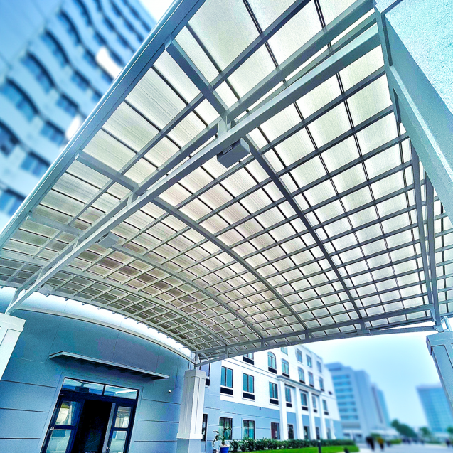 A hotel entrance is covered by a tall, curved ceiling constructed with metal and White Skypoly.